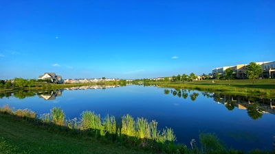 A serene lake within the society reflecting the clear blue sky and nearby trees.