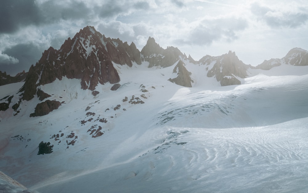 a snow covered mountain range under a cloudy sky