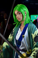 Close-up of a green-haired anime character with large expressive eyes in a vibrant setting.