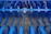 Industrial farming equipment with multiple rows of blue metal discs and blades arranged in a symmetrical pattern, against a gravel surface.