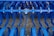 Industrial farming equipment with multiple rows of blue metal discs and blades arranged in a symmetrical pattern, against a gravel surface.