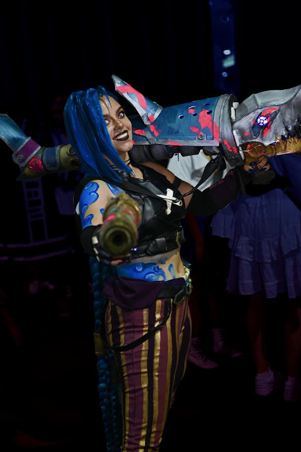 A joyful cosplayer holding their detailed 3D printed figurine at a lively festival.