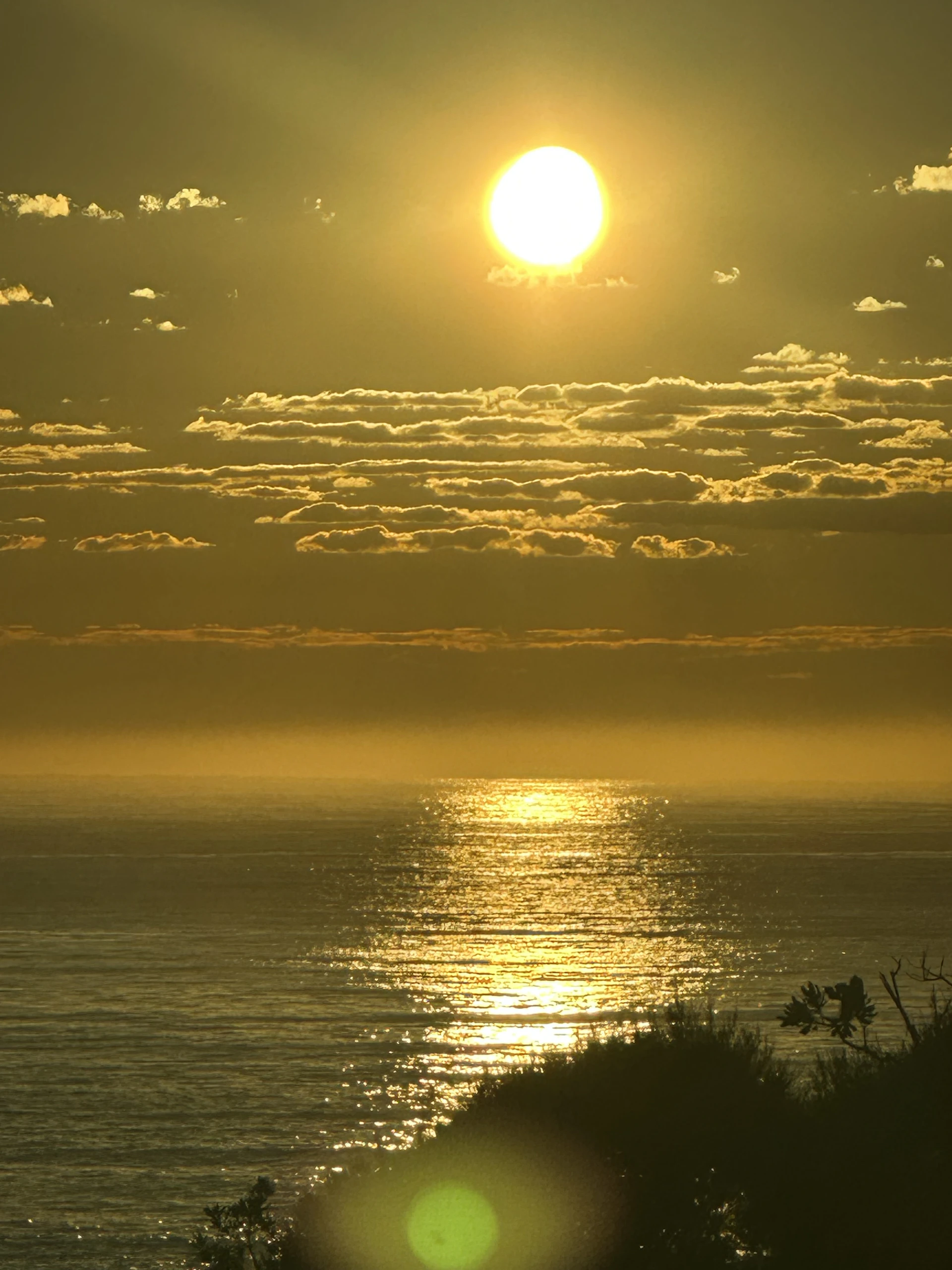 the sun is setting over the ocean on a cloudy day