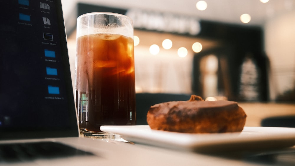 a piece of cake sitting on a plate next to a glass of tea