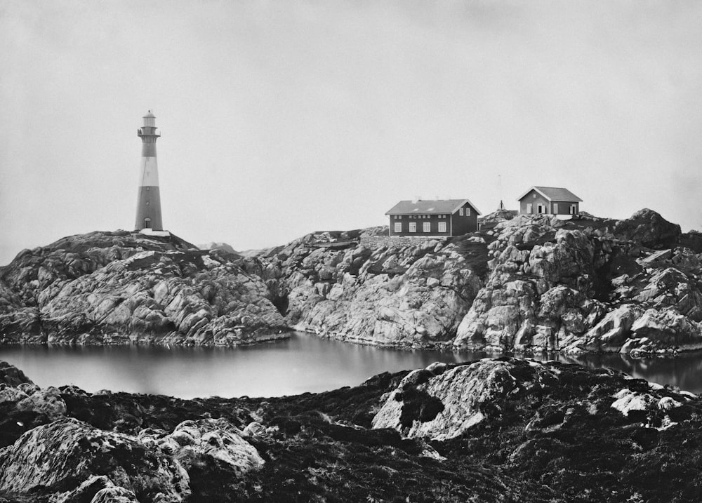 a black and white photo of a lighthouse on top of a mountain