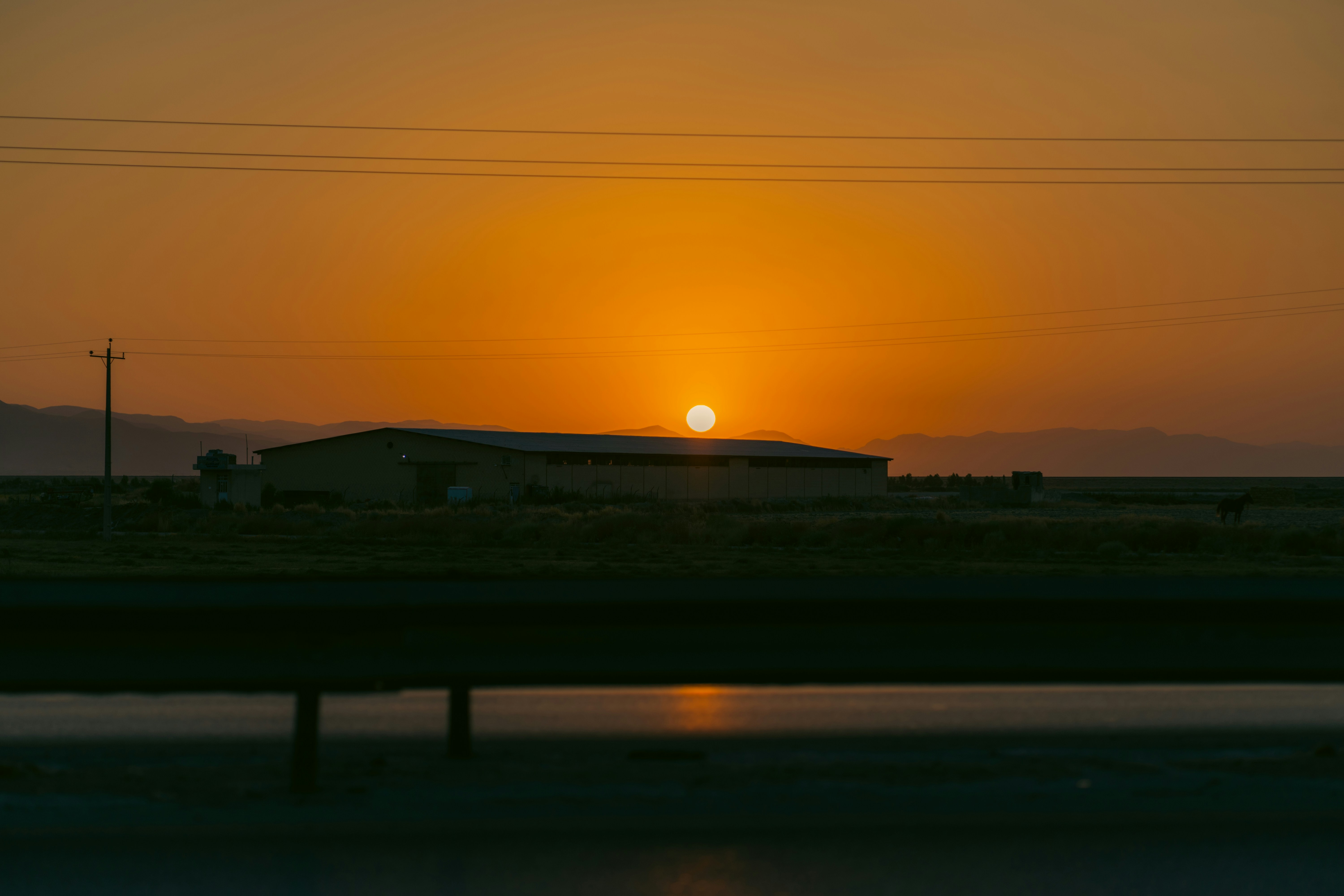 the sun is setting over a small building