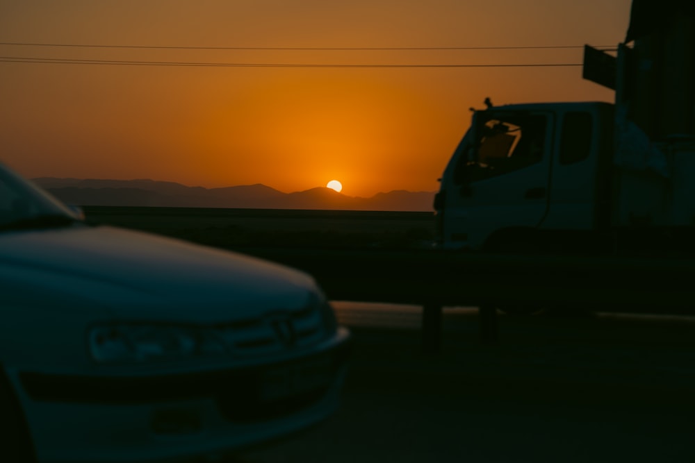 the sun is setting behind a truck on the road
