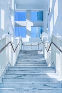 Elegant staircase with white marble steps in a bright, modern building interior.