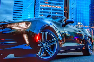 A sleek black sports car parked against a modern city skyline.