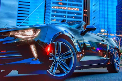 A sleek black sports car parked against a modern city skyline.