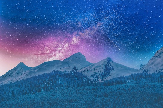 A breathtaking night sky filled with stars and a visible Milky Way spans above snow-covered mountains. A shooting star streaks across the vibrant sky, showcasing shades of purple, pink, and deep blue. The silhouettes of forest trees line the bottom of the image, creating a serene and awe-inspiring landscape.