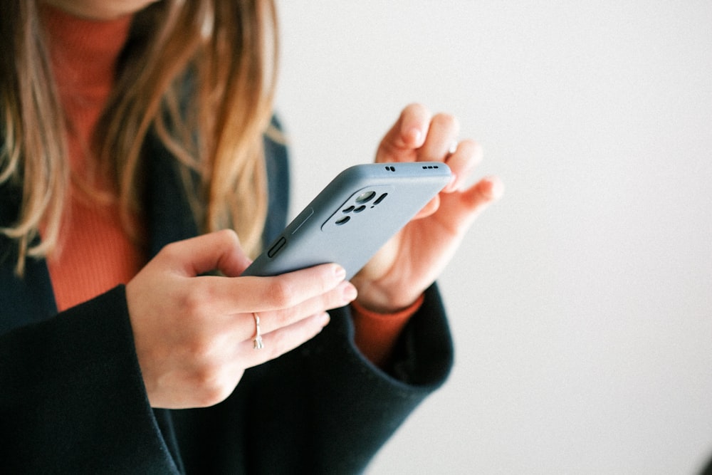 Una mujer sosteniendo un teléfono celular en sus manos