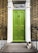 A green front door with a brass knocker and mail slot sits in a brick wall, framed by white molding. The door has the number 45 above it. A striped cat is sitting on the stone doorstep, surrounded by black metal railings.