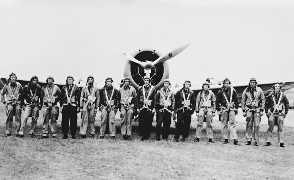 a group of men standing in front of an airplane