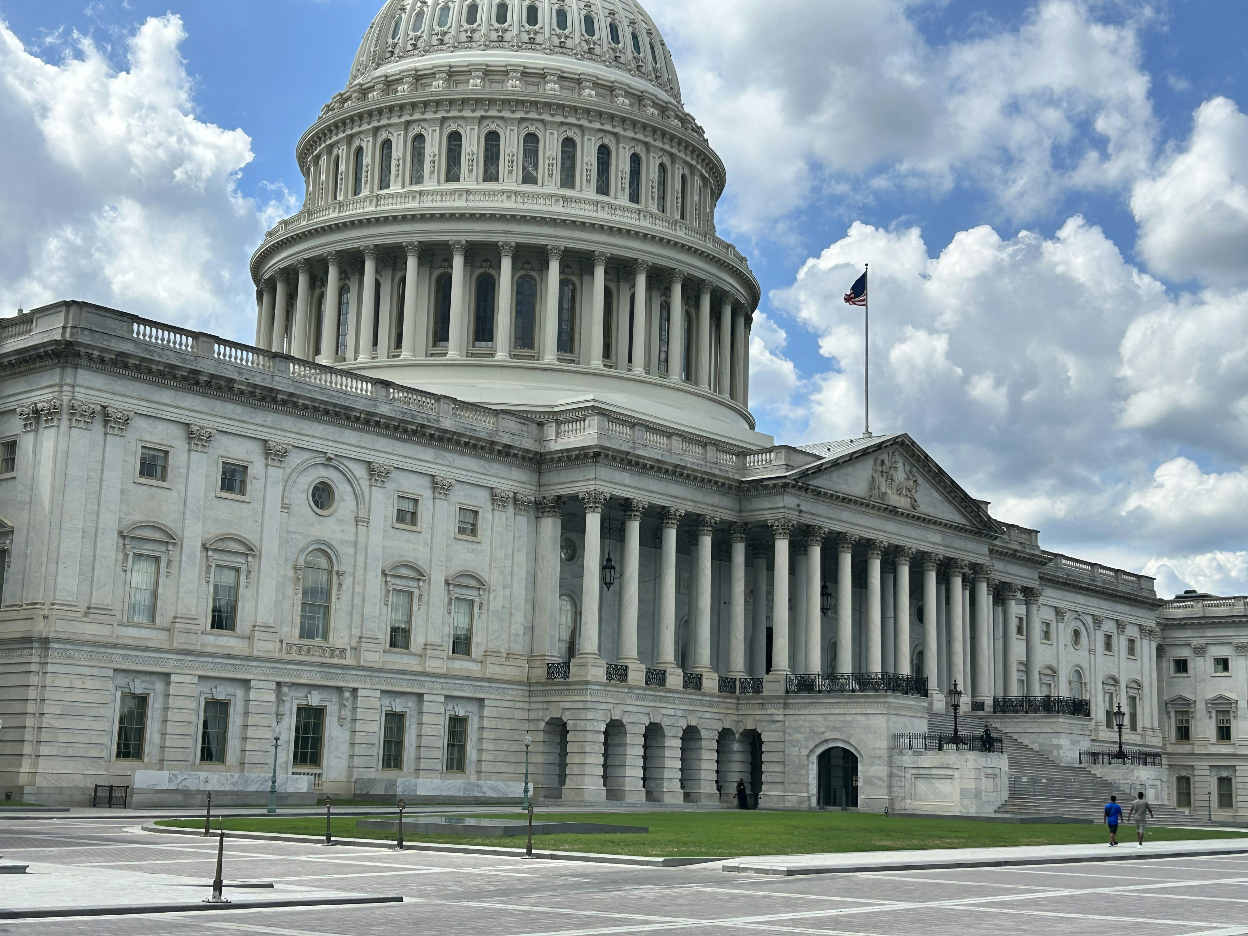 US Capitol building with American flag and clear blue sky