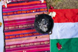 Flat lay of a huipil displayed on a rustic wooden table with natural dye pots nearby.