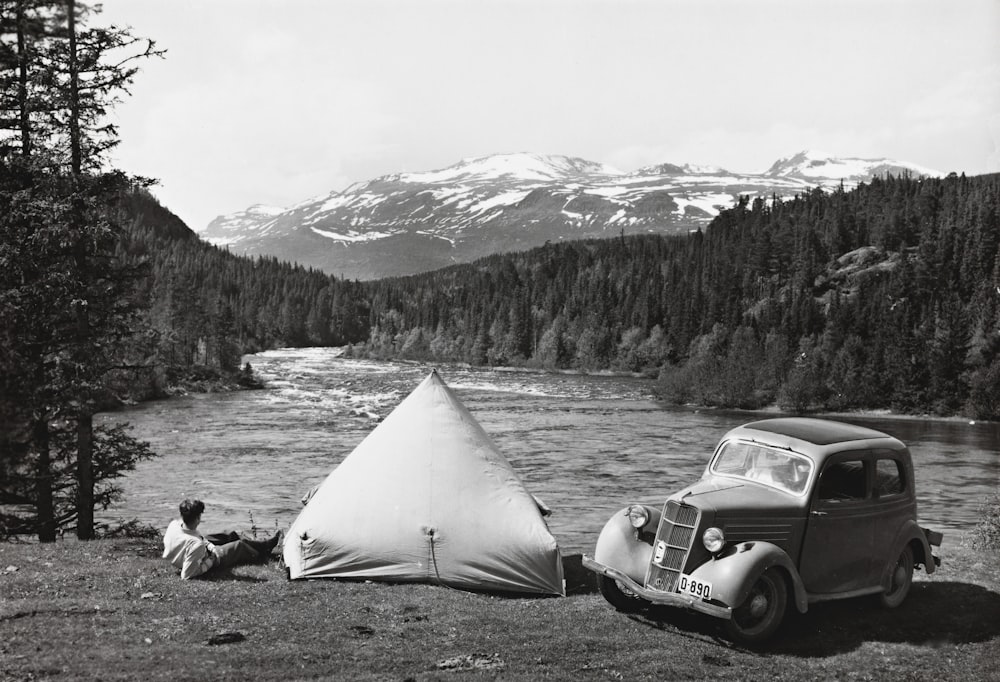 a car parked next to a tent near a river