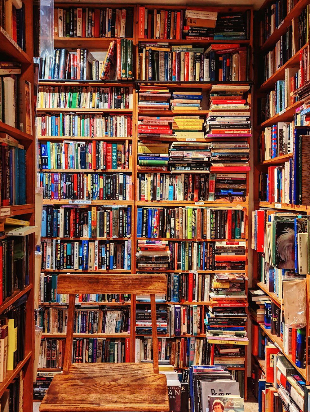 a bookshelf filled with lots of books next to a wooden bench