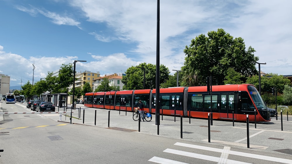 a red train traveling down a street next to tall buildings