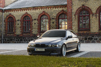 A sleek sedan parked in front of a historic Jhansi landmark on a sunny day.
