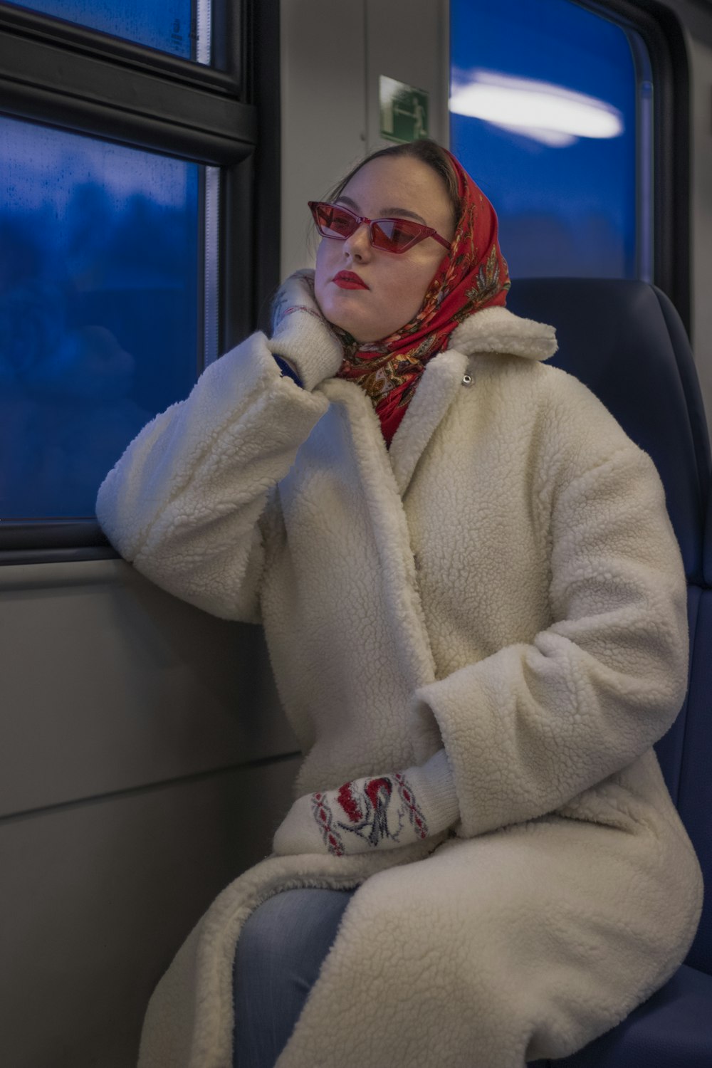 a woman in a white coat sitting on a train