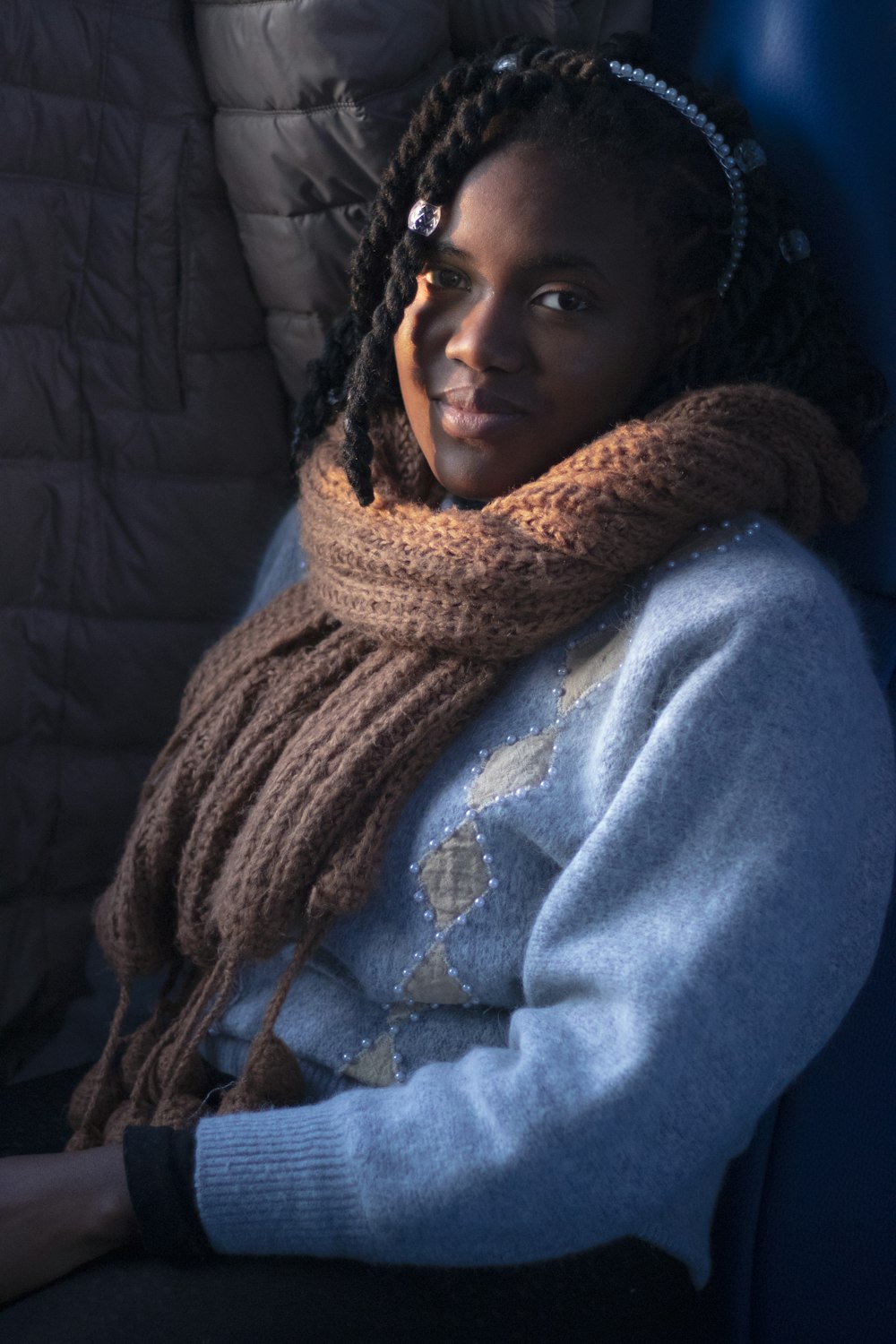 a woman sitting in a chair with a scarf around her neck