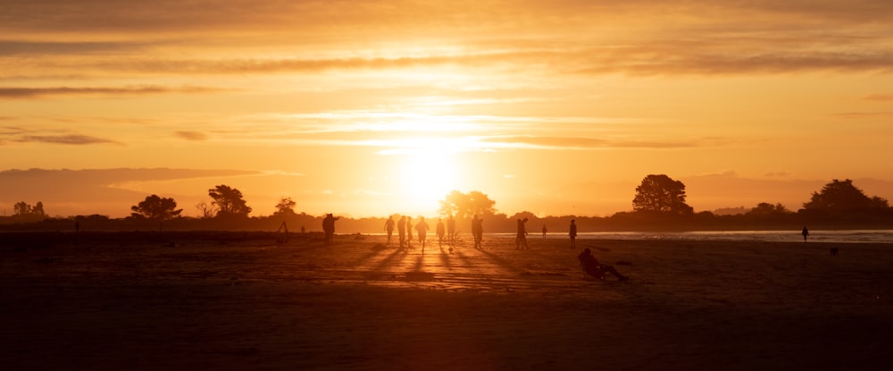 um grupo de pessoas caminhando por uma estrada de terra ao pôr do sol