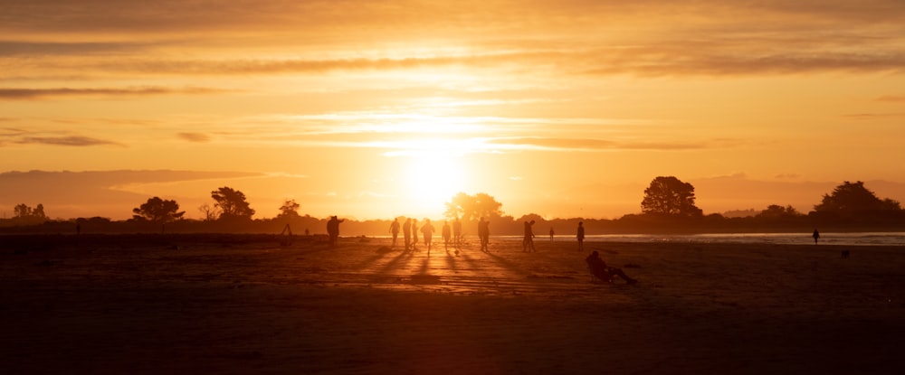a group of people walking down a dirt road at sunset