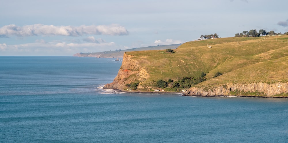 a large body of water sitting next to a lush green hillside