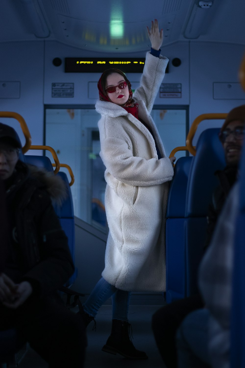 a woman in a white coat waving on a bus