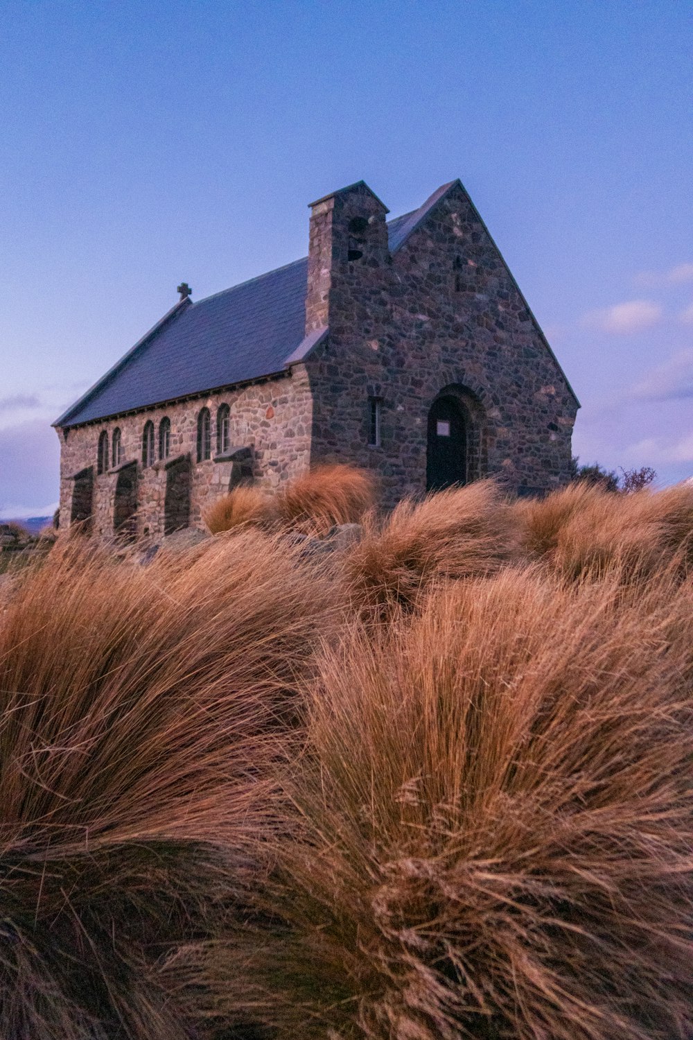 a stone church with tall grass in front of it