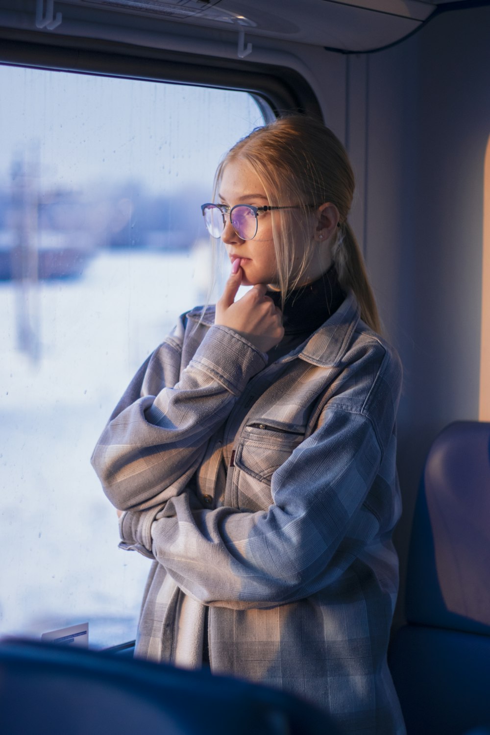 a woman wearing glasses is looking out the window