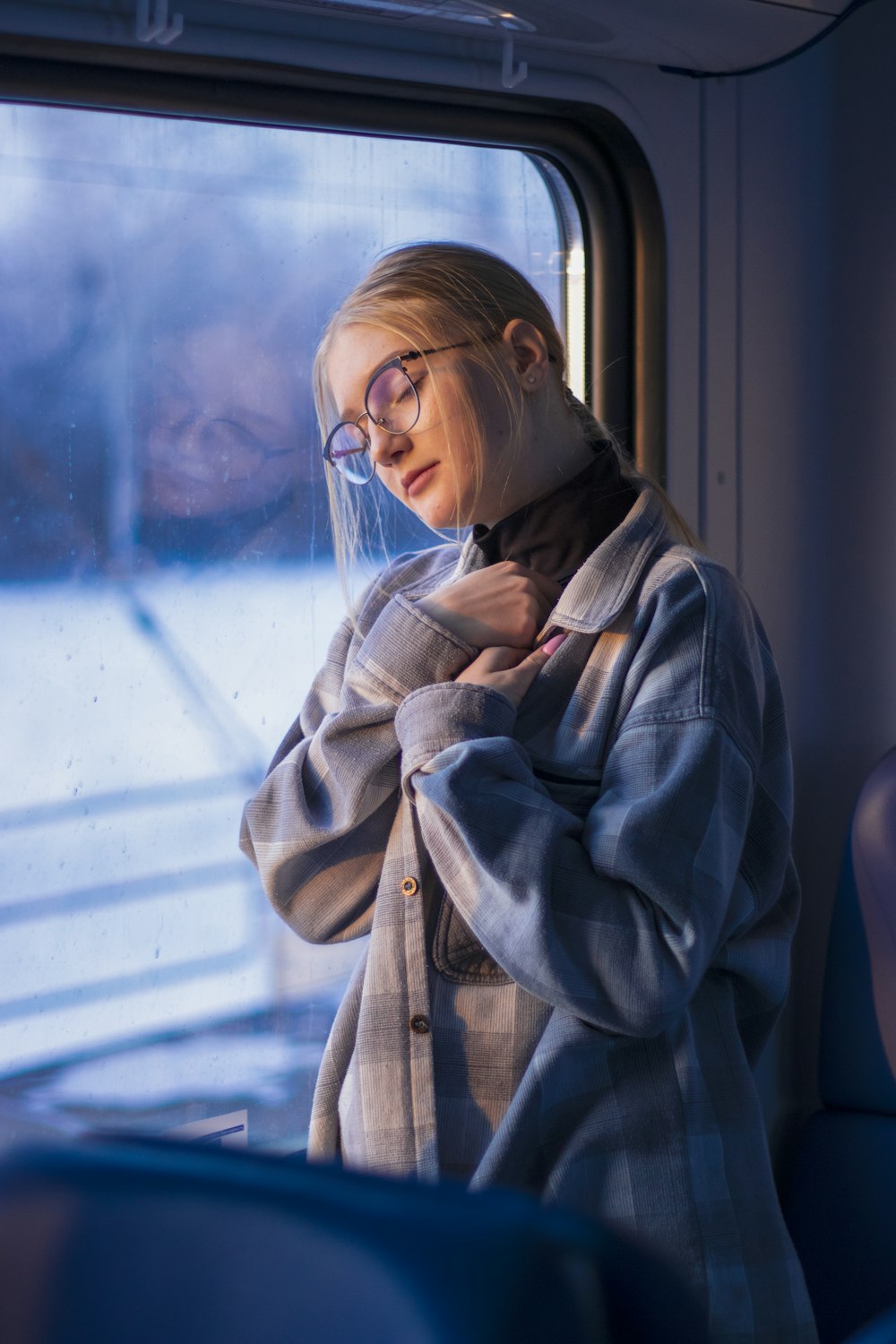 a woman wearing glasses is looking out the window