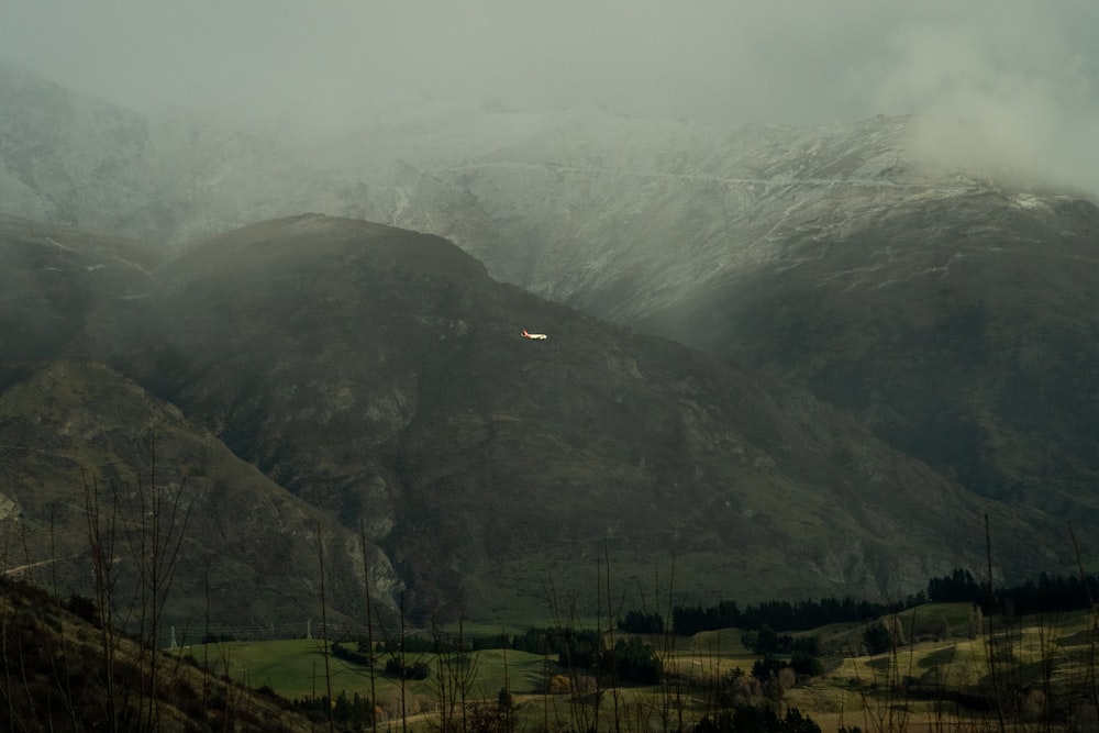 a view of a mountain range with a plane flying in the sky