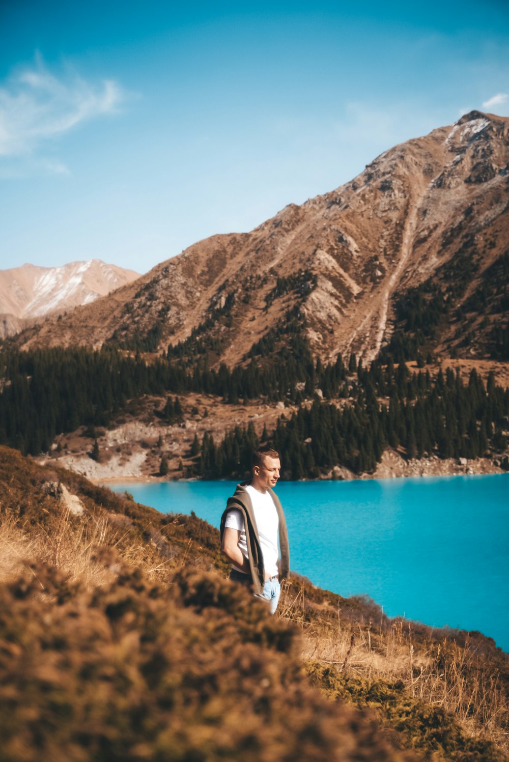 a man standing on a hill next to a lake