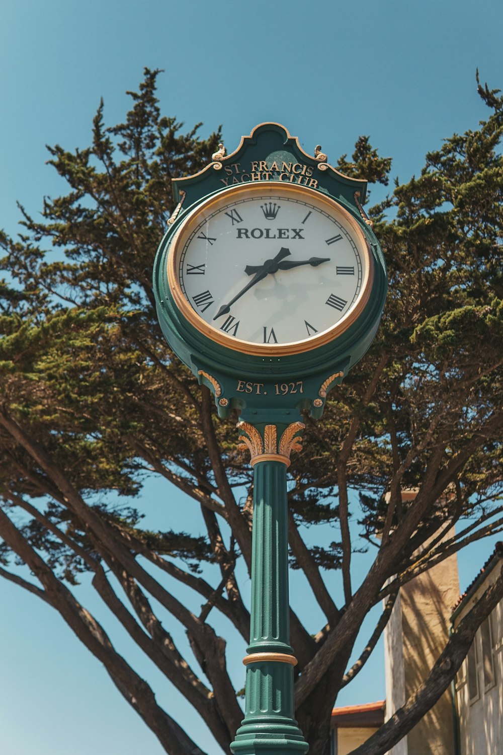 a green pole with a clock on top of it