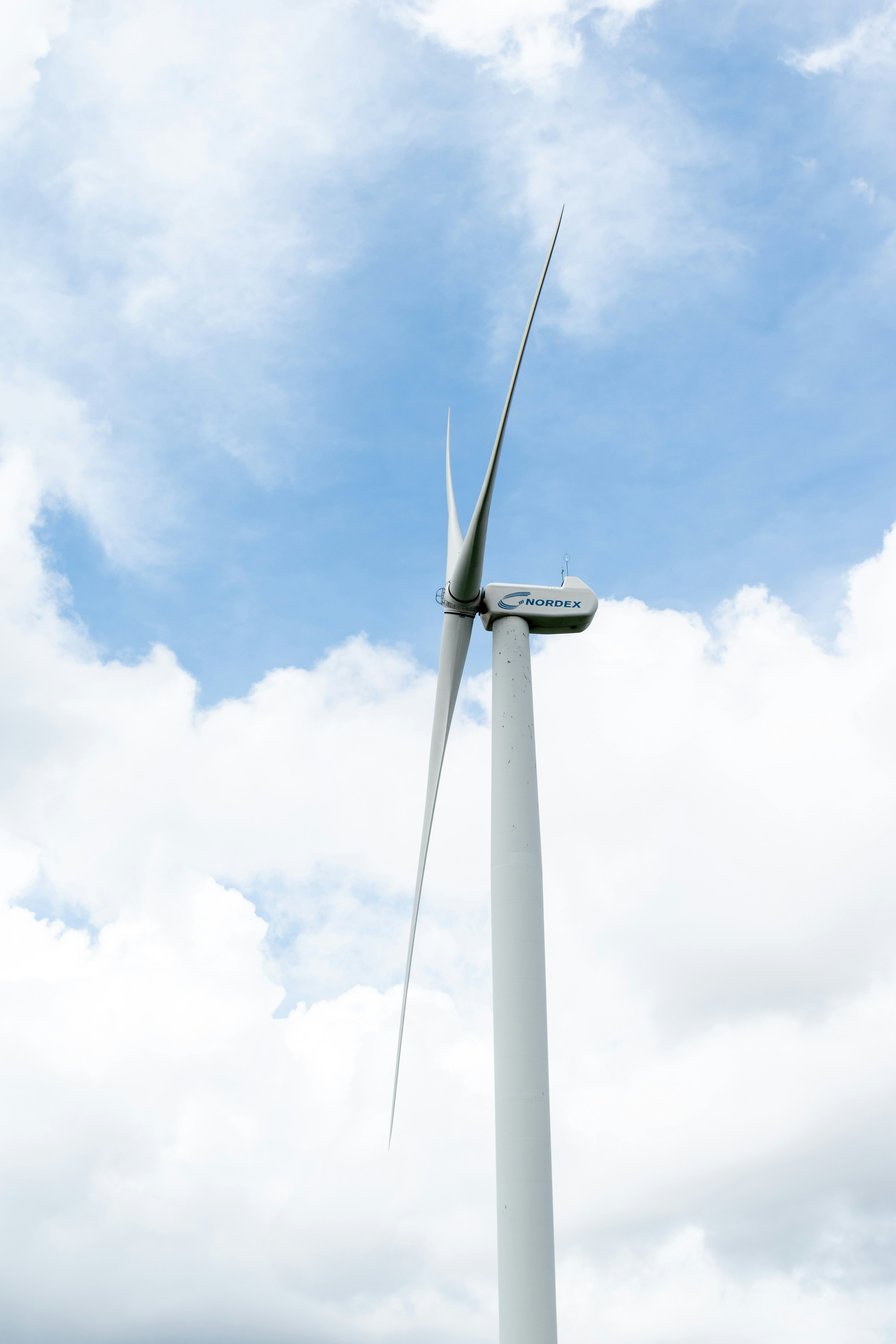 Small residential wind turbine spinning against blue sky with white clouds