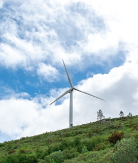 A wind turbine standing tall in a green landscape.