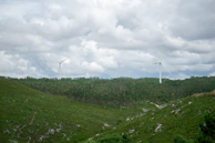 Technicians inspecting a wind turbine blade against a backdrop of rolling green hills.