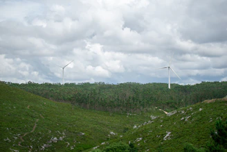 Technicians inspecting a wind turbine blade against a backdrop of rolling green hills.
