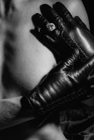 Close-up of stylish accessories: leather gloves, a silver collar, and a delicate yet commanding hand gesture.