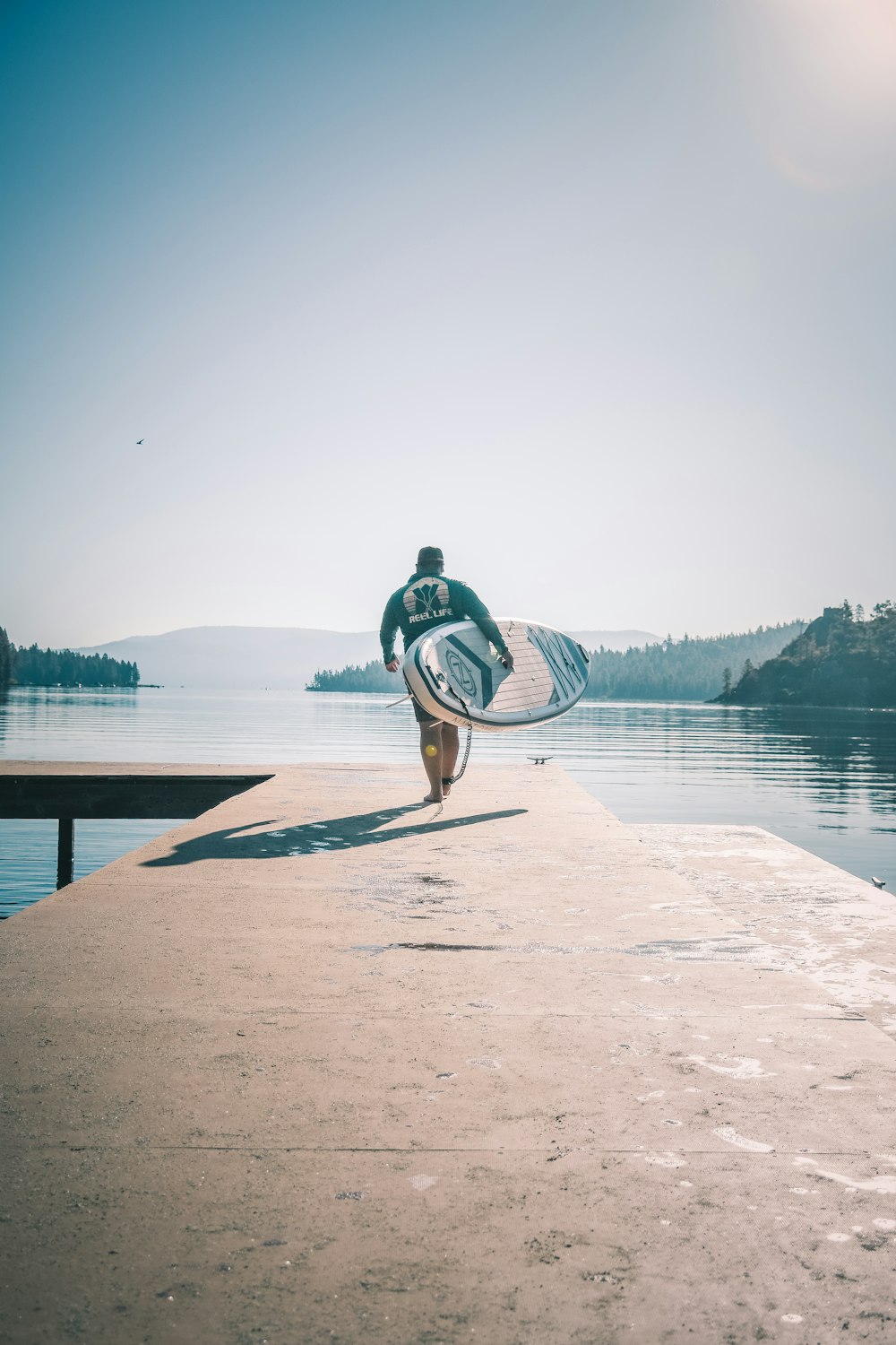 a man carrying a surfboard on top of a pier