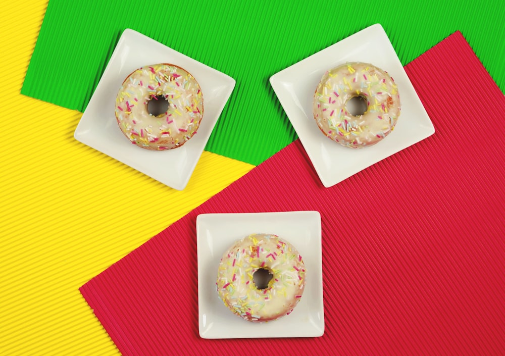 two donuts with sprinkles on a white plate