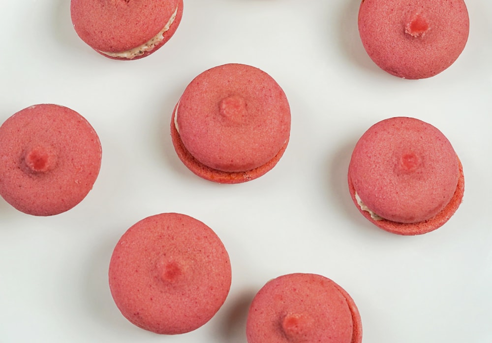 a white plate topped with pink macaroons on top of a table