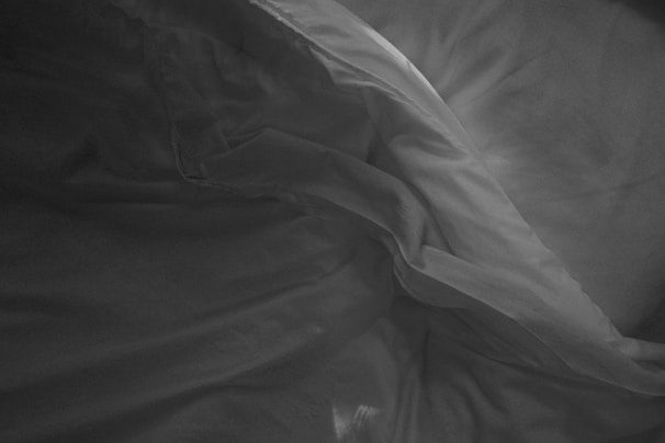 A crumpled piece of fabric with shadows and highlights, creating flowing lines and soft textures. The material appears lightweight with a smooth, silky surface.