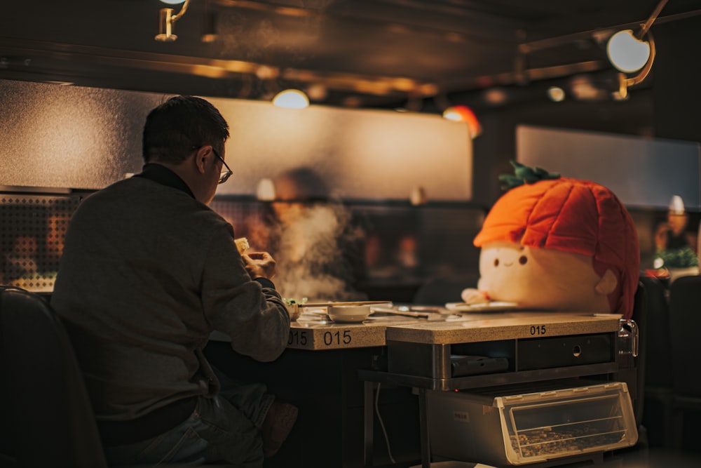 a man sitting at a table with a fake head on top of it