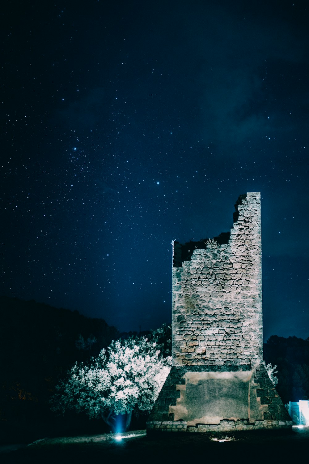 a tall tower sitting next to a forest under a night sky