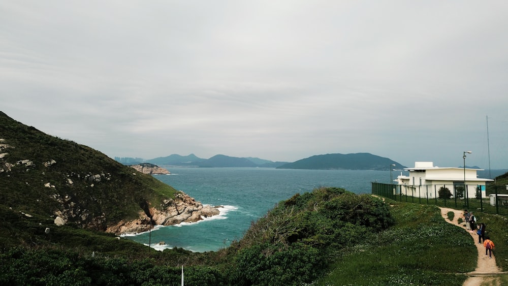 a group of people walking up a hill next to a body of water