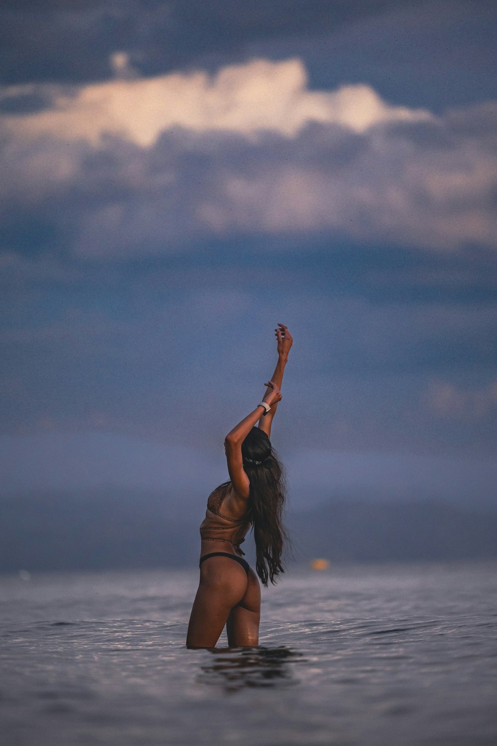 uma mulher está de pé na água com os braços no ar