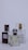 Three perfume bottles are arranged closely together against a plain background. Each bottle has a unique design with varied labels and caps, showcasing different brands and styles.